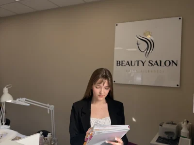 Pracowniczka salonu z dokumentami przy ścianie z logo